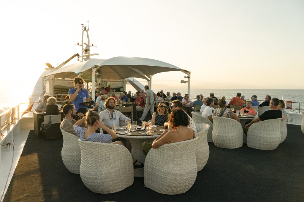 Guests aboard Coral Discoverer waiting BBQ dinner service on the sun deck