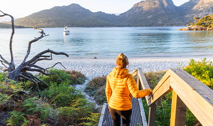 Woman walking down stairs onto a scenic beach in Tasmania